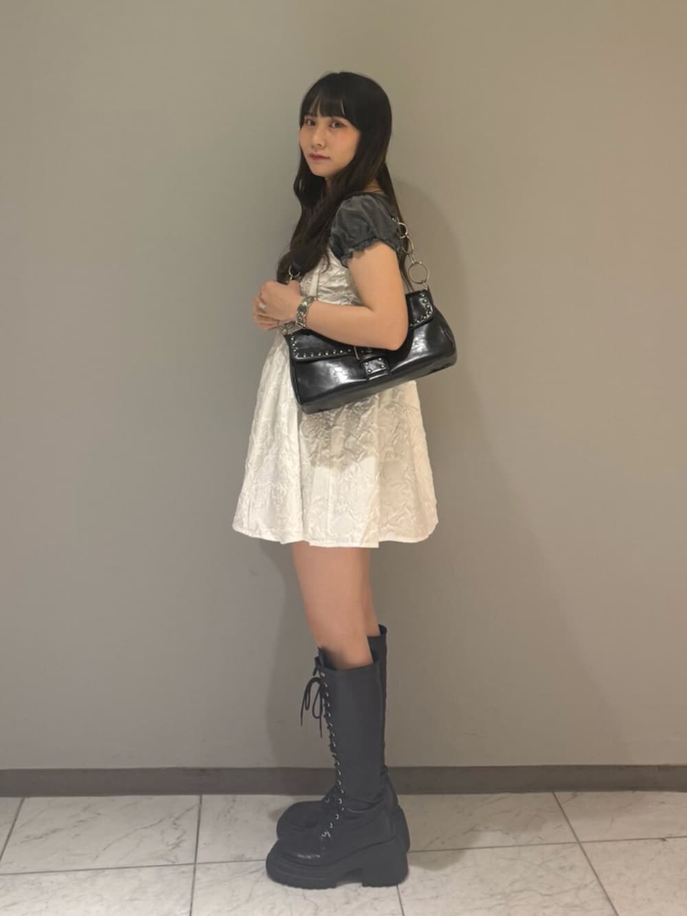 ブラック系のハンドバッグ、ブラック系のブーツ、グレー系のTシャツ/カットソーを着用したレディースの夏コーディネートの2枚目の写真