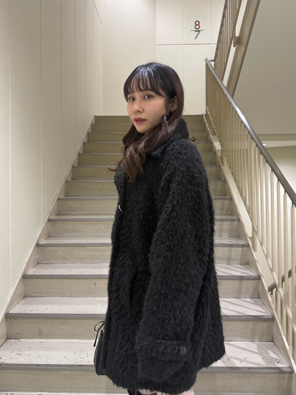 ブラック系のステンカラーコート、ブラック系のハンドバッグ、ブラック系のブーツを着用したレディースの冬コーディネートの7枚目の写真