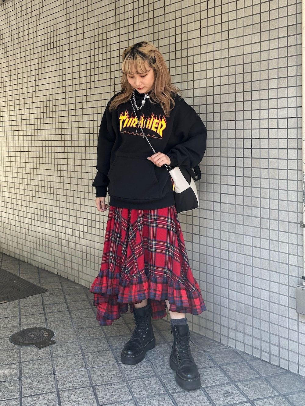 レッド系のスカート、ブラック系のパーカー、ブラック系のハンドバッグを着用したレディースの秋コーディネートの2枚目の写真