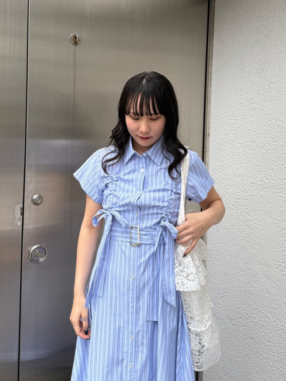 ブラック系のブーツ、ブルー系のワンピース、ホワイト系のトートバッグを着用したレディースの春コーディネートの6枚目の写真