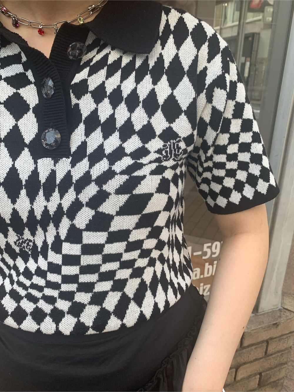 ブラック系のニット/セーター、ブラック系のスカート、シルバー系のブレスレットを着用したレディースの春コーディネートの5枚目の写真