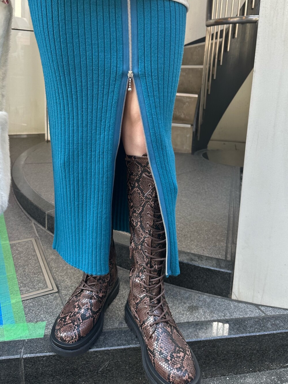 グレー系のスウェット、ブルー系のスカート、その他のブーツを着用したレディースの秋コーディネートの7枚目の写真