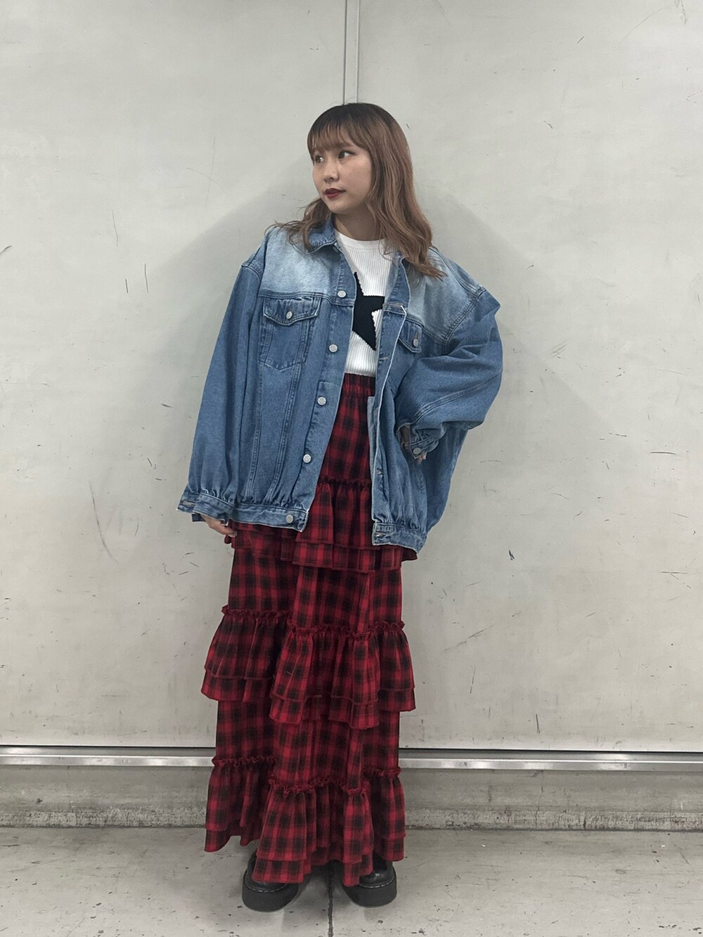 ブルー系のデニムジャケット、ホワイト系のニット/セーター、レッド系のスカートを着用したレディースの春コーディネートの3枚目の写真