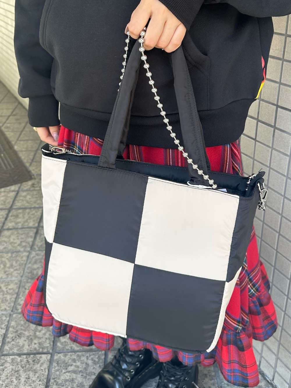 レッド系のスカート、ブラック系のパーカー、ブラック系のハンドバッグを着用したレディースの秋コーディネートの7枚目の写真