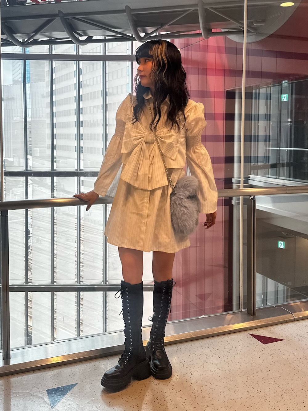 ホワイト系のシャツワンピース、ブルー系のハンドバッグ、ブラック系のブーツを着用したレディースの夏コーディネートの2枚目の写真