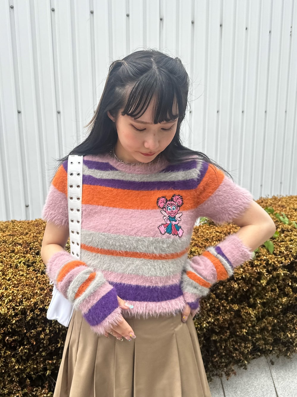 ピンク系のニット/セーター、ベージュ系のスカート、ホワイト系のショルダーバッグを着用したレディースの夏コーディネートの5枚目の写真