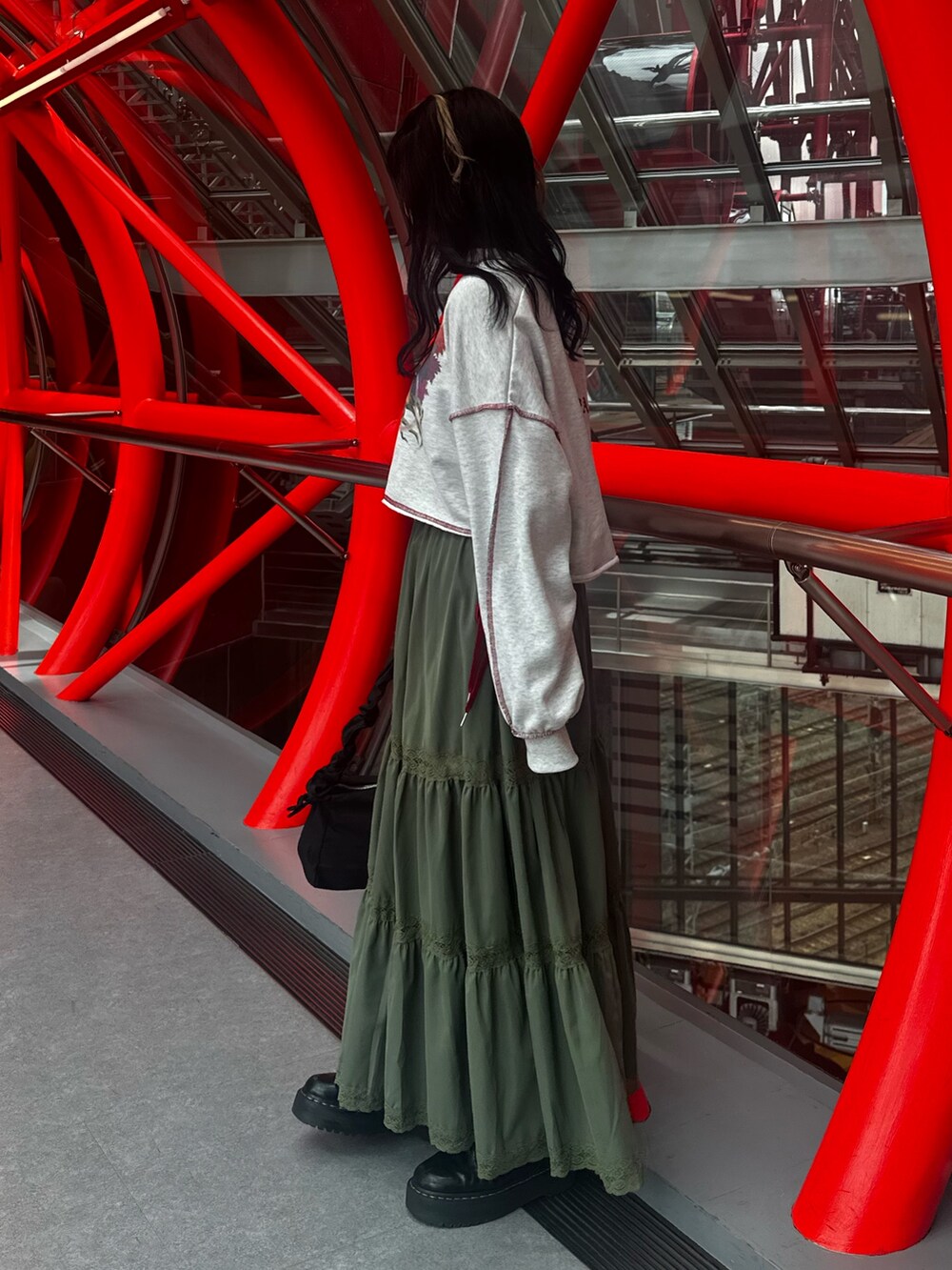 グレー系のスウェット、グリーン系のスカート、ブラック系のショルダーバッグを着用したレディースの夏コーディネートの2枚目の写真