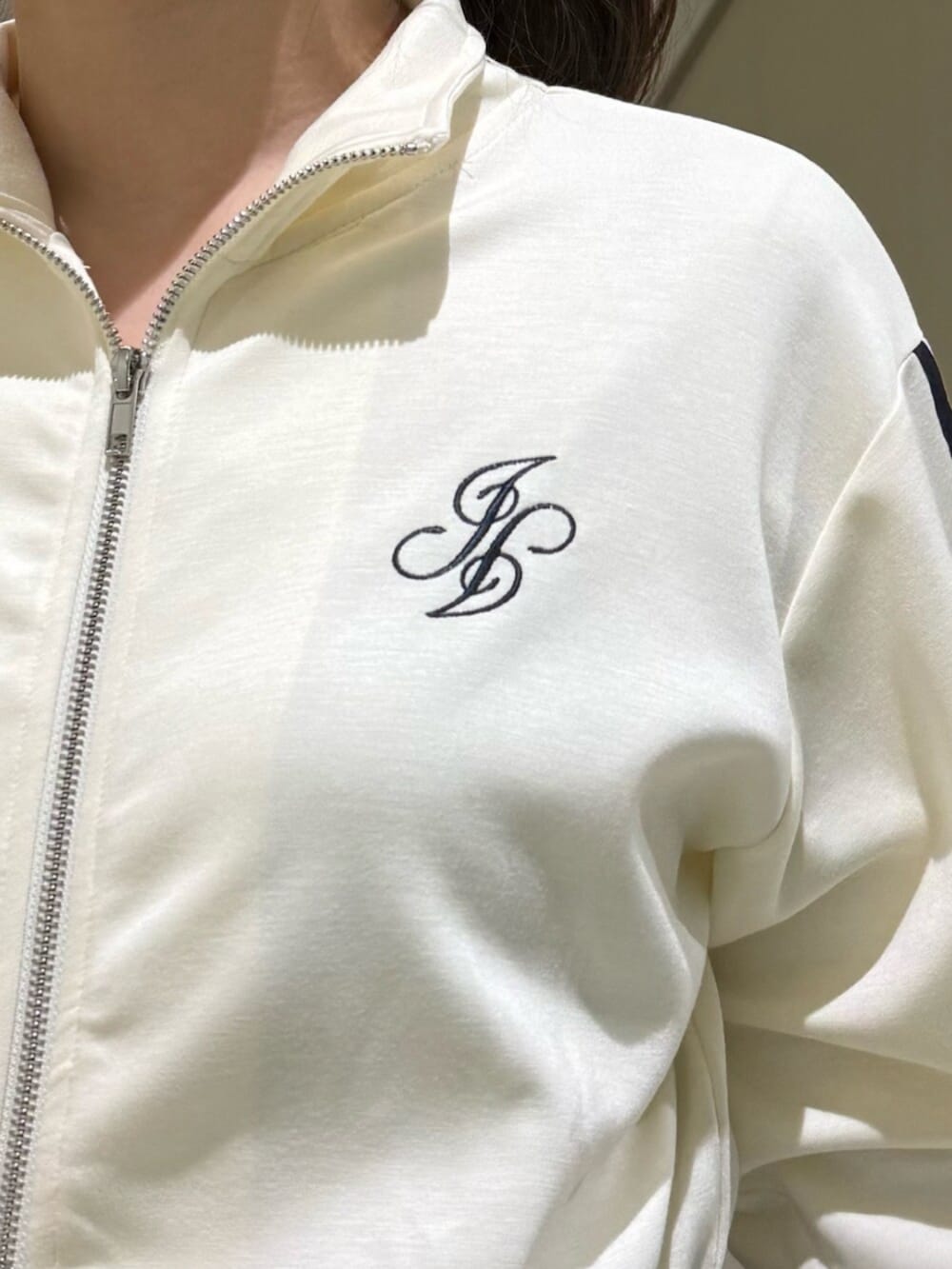 ブラック系のブーツ、ホワイト系のジャージ、ホワイト系のスカートを着用したレディースの冬コーディネートの9枚目の写真