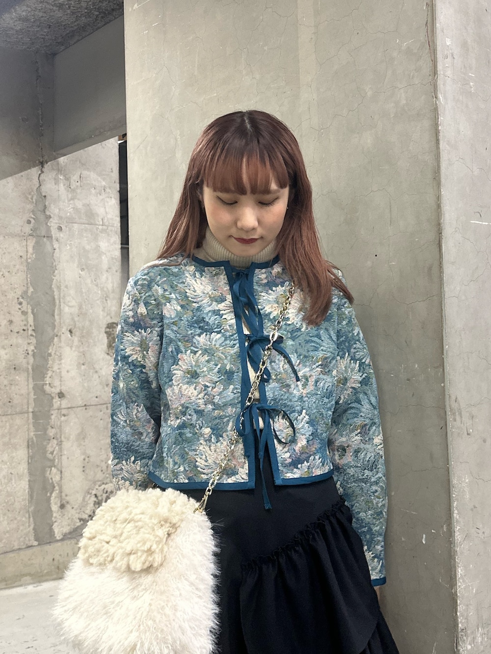 ブラック系のスカート、ブルー系のノーカラージャケット、ホワイト系のハンドバッグを着用したレディースの冬コーディネートの4枚目の写真