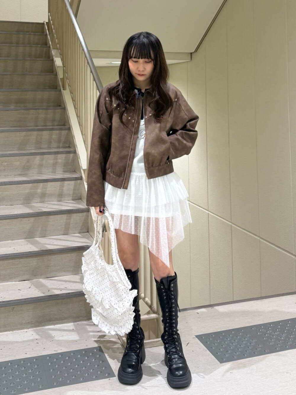 ブラック系のブーツ、ブラウン系のブルゾン、ホワイト系のワンピースを着用したレディースの冬コーディネートの3枚目の写真