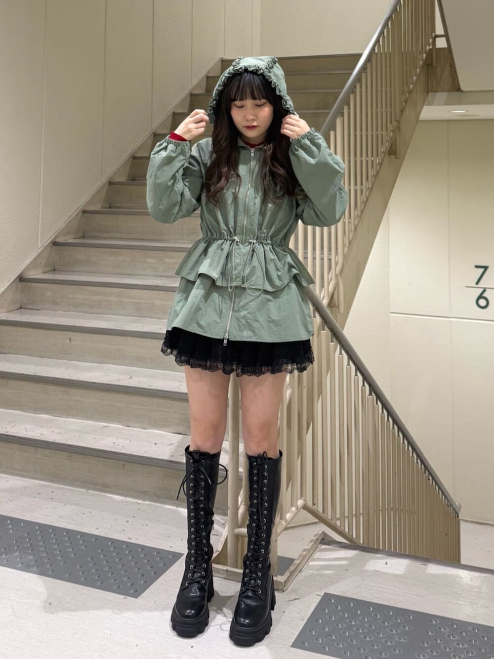 ブラック系のブーツ、グリーン系のナイロンジャケット、ブラック系のその他パンツを着用したレディースの春コーディネートの6枚目の写真