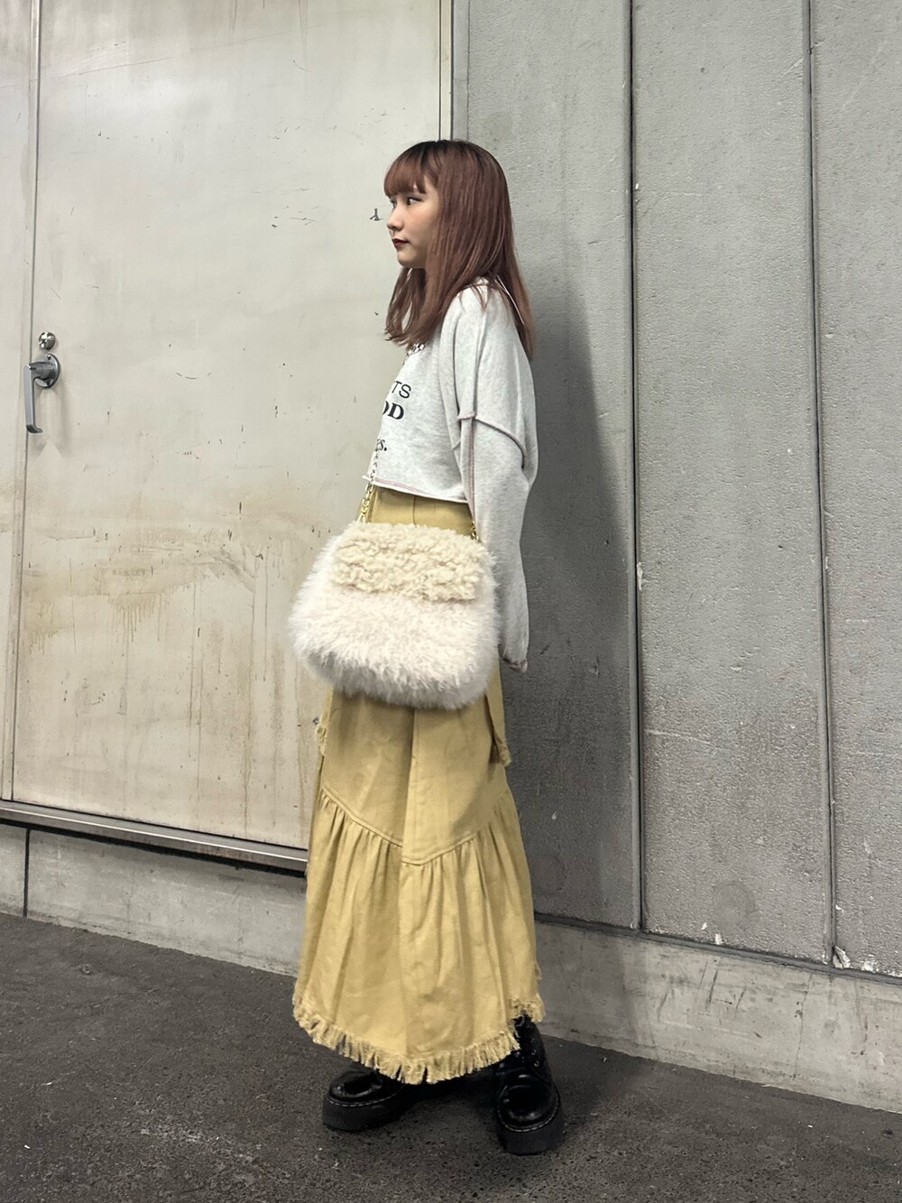 グレー系のスウェット、ホワイト系のハンドバッグ、ベージュ系のスカートを着用したレディースの冬コーディネートの2枚目の写真