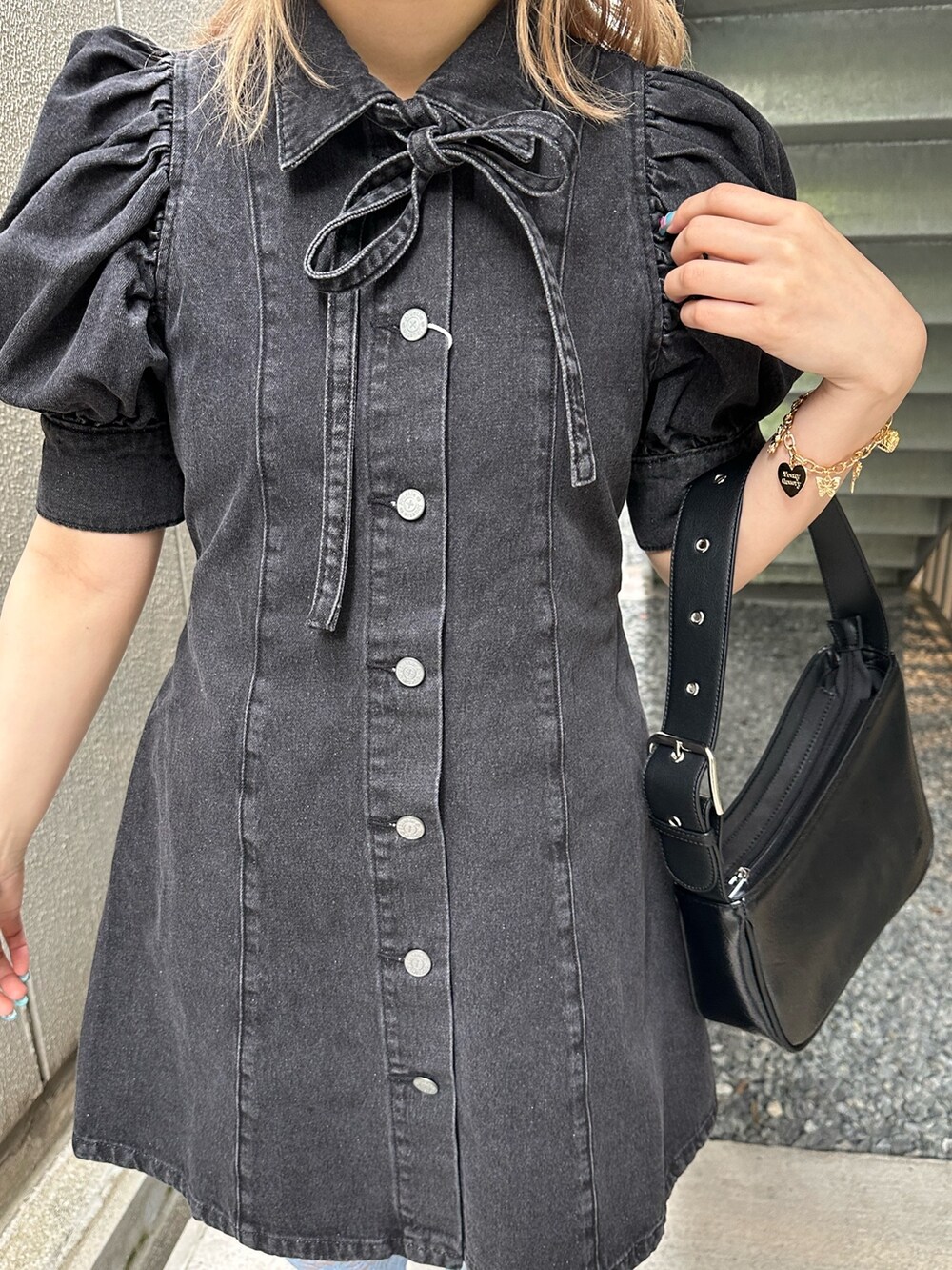 ブラック系のワンピース、ブラック系のハンドバッグ、ゴールド系のピアス（両耳用）を着用したレディースの春コーディネートの5枚目の写真