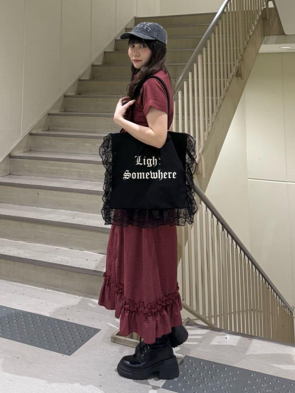 ブラック系のトートバッグ、レッド系のワンピース、ブラック系のブーツを着用したレディースの春コーディネートの3枚目の写真