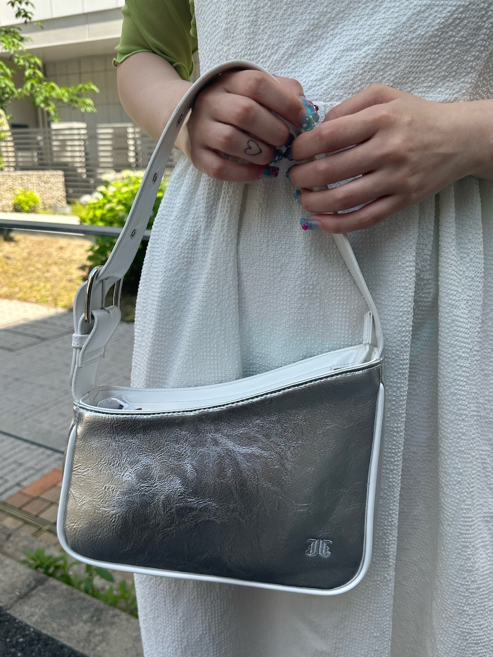 シルバー系のハンドバッグ、ブラック系のブーツ、ホワイト系のワンピースを着用したレディースの春コーディネートの6枚目の写真