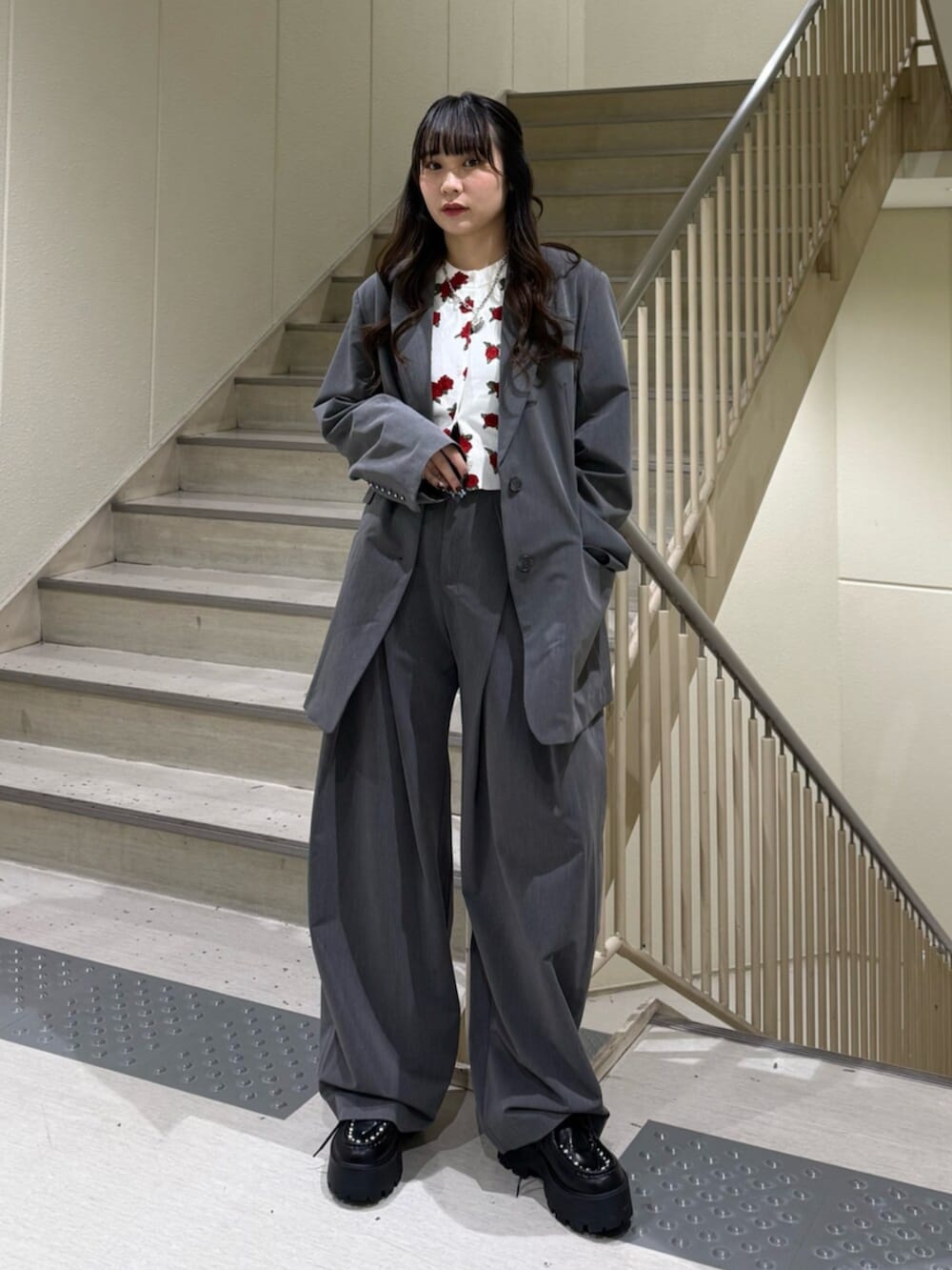 グレー系のスラックス、グレー系のテーラードジャケット、ホワイト系のカーディガン/ボレロを着用したレディースの冬コーディネートの2枚目の写真