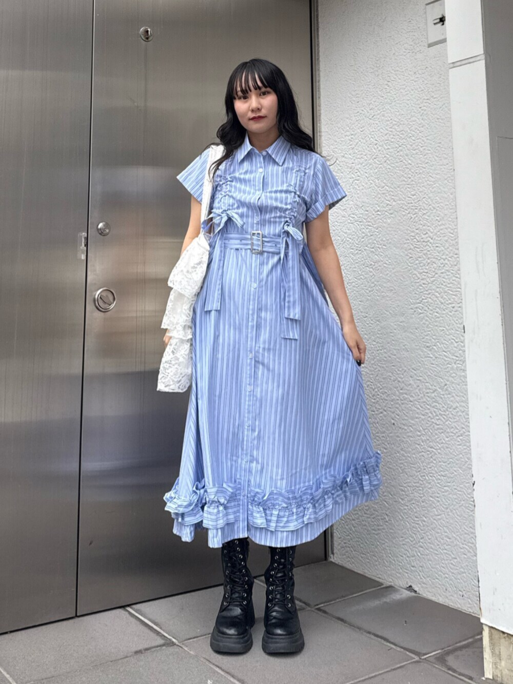 ブラック系のブーツ、ブルー系のワンピース、ホワイト系のトートバッグを着用したレディースの春コーディネートの5枚目の写真