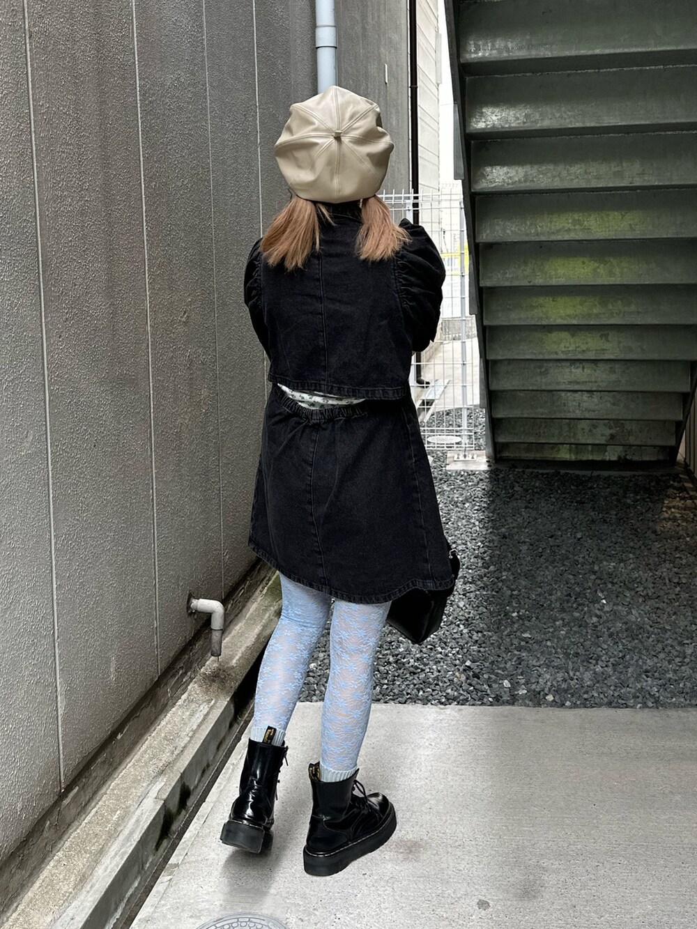 ブラック系のワンピース、ブラック系のハンドバッグ、ゴールド系のピアス（両耳用）を着用したレディースの春コーディネートの3枚目の写真