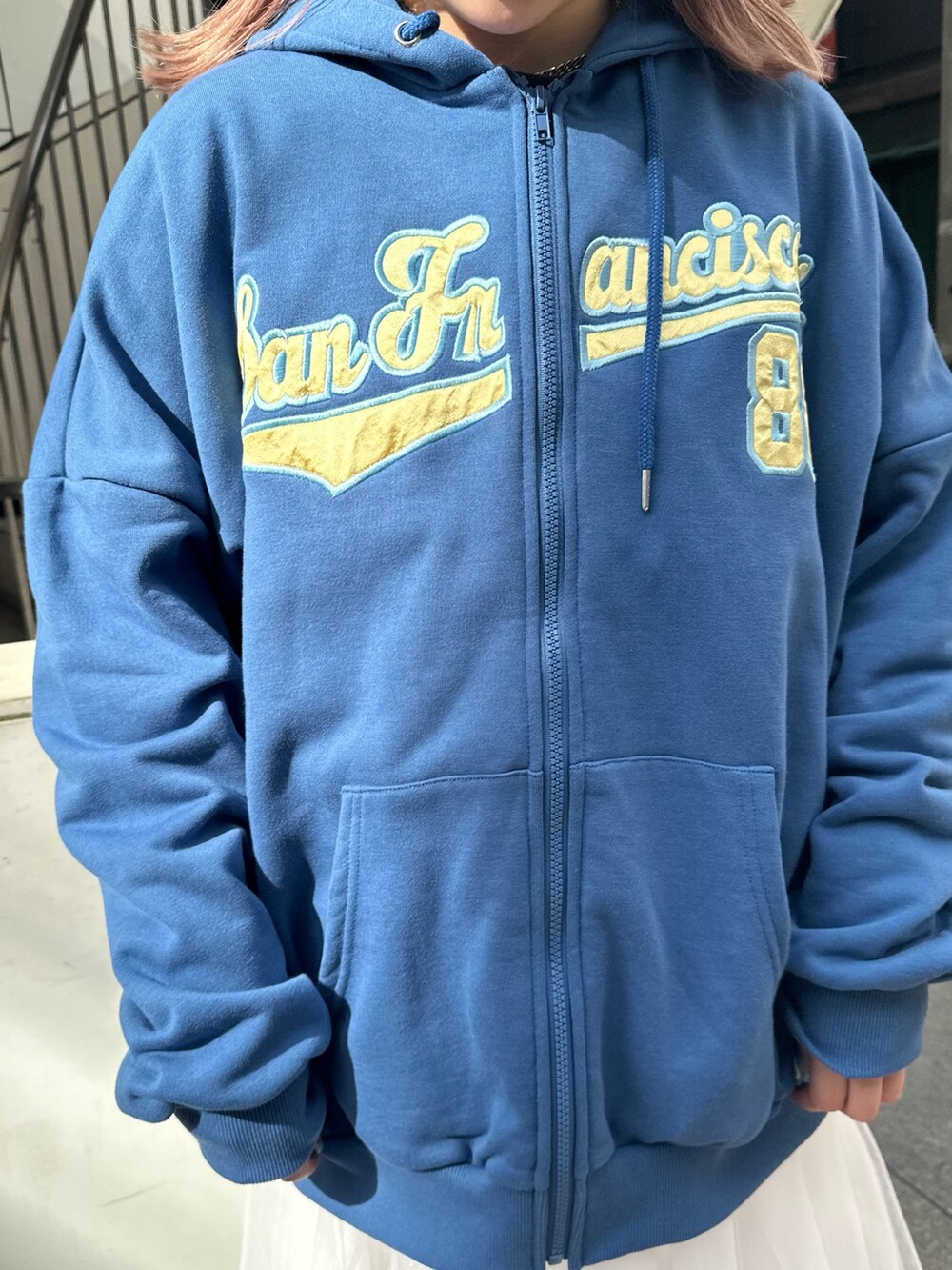 ブルー系のパーカー、ホワイト系のスカート、ブラック系のブーツを着用したレディースの春コーディネートの5枚目の写真