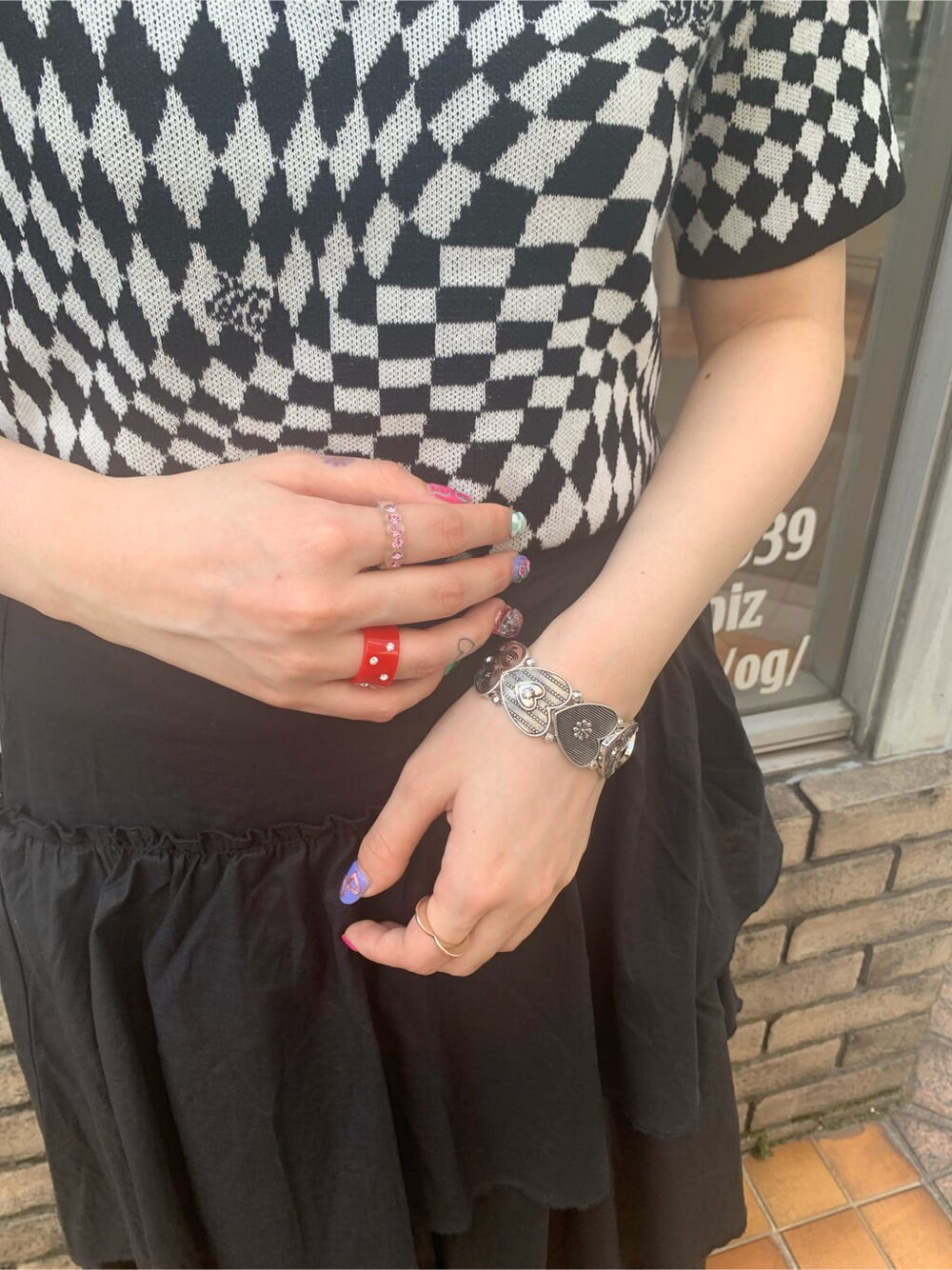 ブラック系のニット/セーター、ブラック系のスカート、シルバー系のブレスレットを着用したレディースの春コーディネートの4枚目の写真