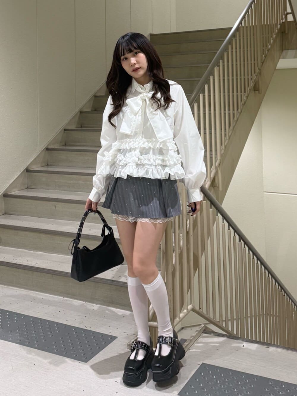 ブラック系のハンドバッグ、ブラック系のローファー、グレー系のスカートを着用したレディースの冬コーディネートの2枚目の写真