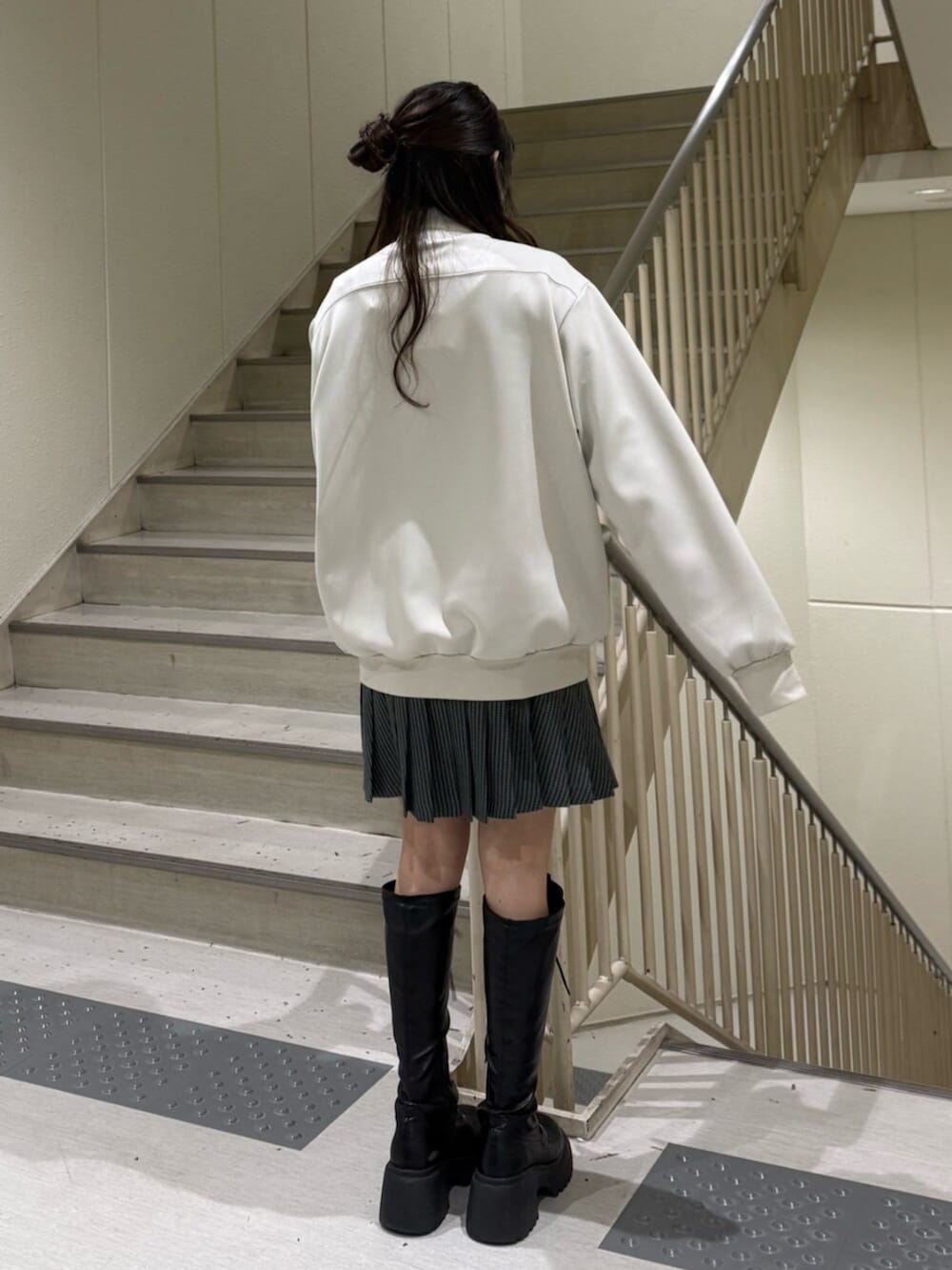 ブラック系のブーツ、ホワイト系のジャージ、その他のスカートを着用したレディースの冬コーディネートの5枚目の写真