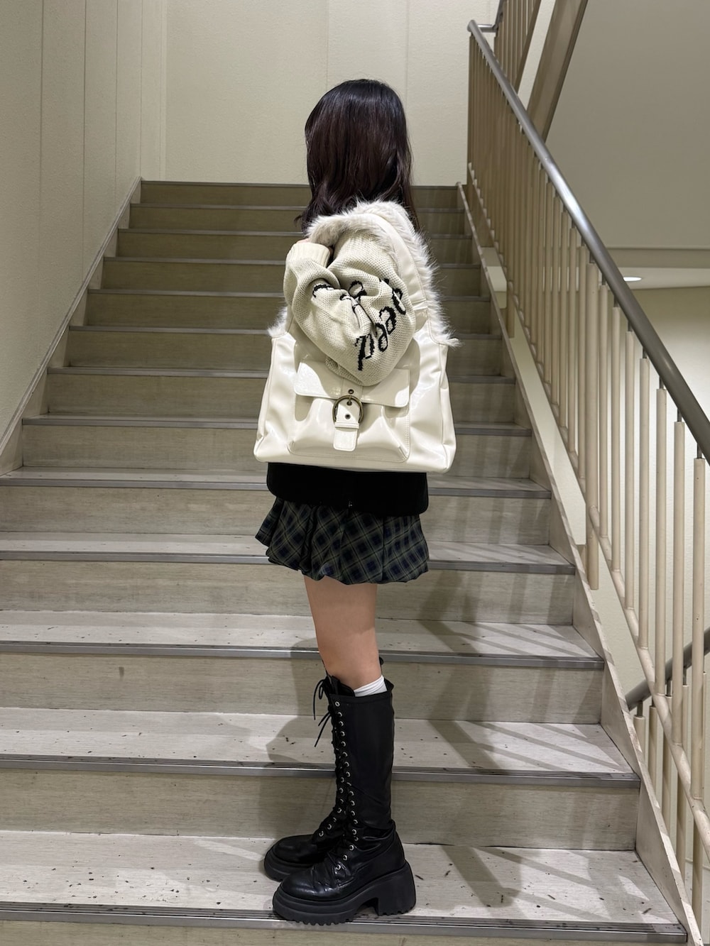 ブラック系のニット/セーター、グリーン系のワンピース、ホワイト系のハンドバッグを着用したレディースの冬コーディネートの4枚目の写真