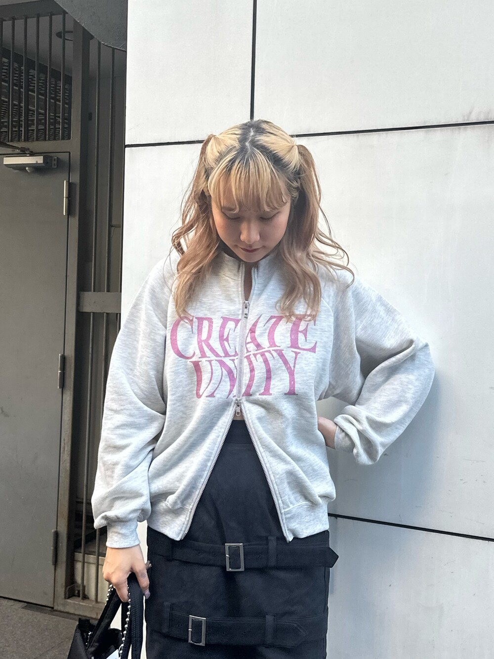 グレー系のスウェット、ブラック系のスカート、ブラック系のハンドバッグを着用したレディースの秋コーディネートの4枚目の写真