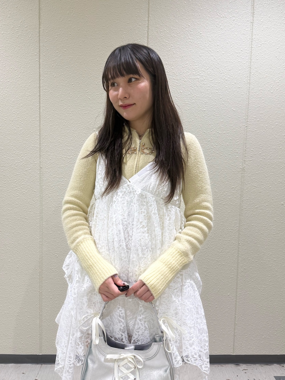 イエロー系のパーカー、ホワイト系のワンピース、シルバー系のハンドバッグを着用したレディースの冬コーディネートの6枚目の写真