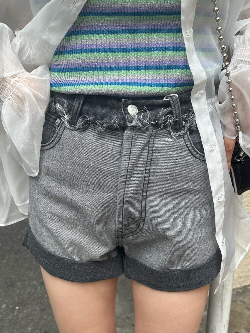 ブラック系のブーツ、ブラック系のデニムパンツ、ホワイト系のシャツ/ブラウスを着用したレディースの夏コーディネートの6枚目の写真