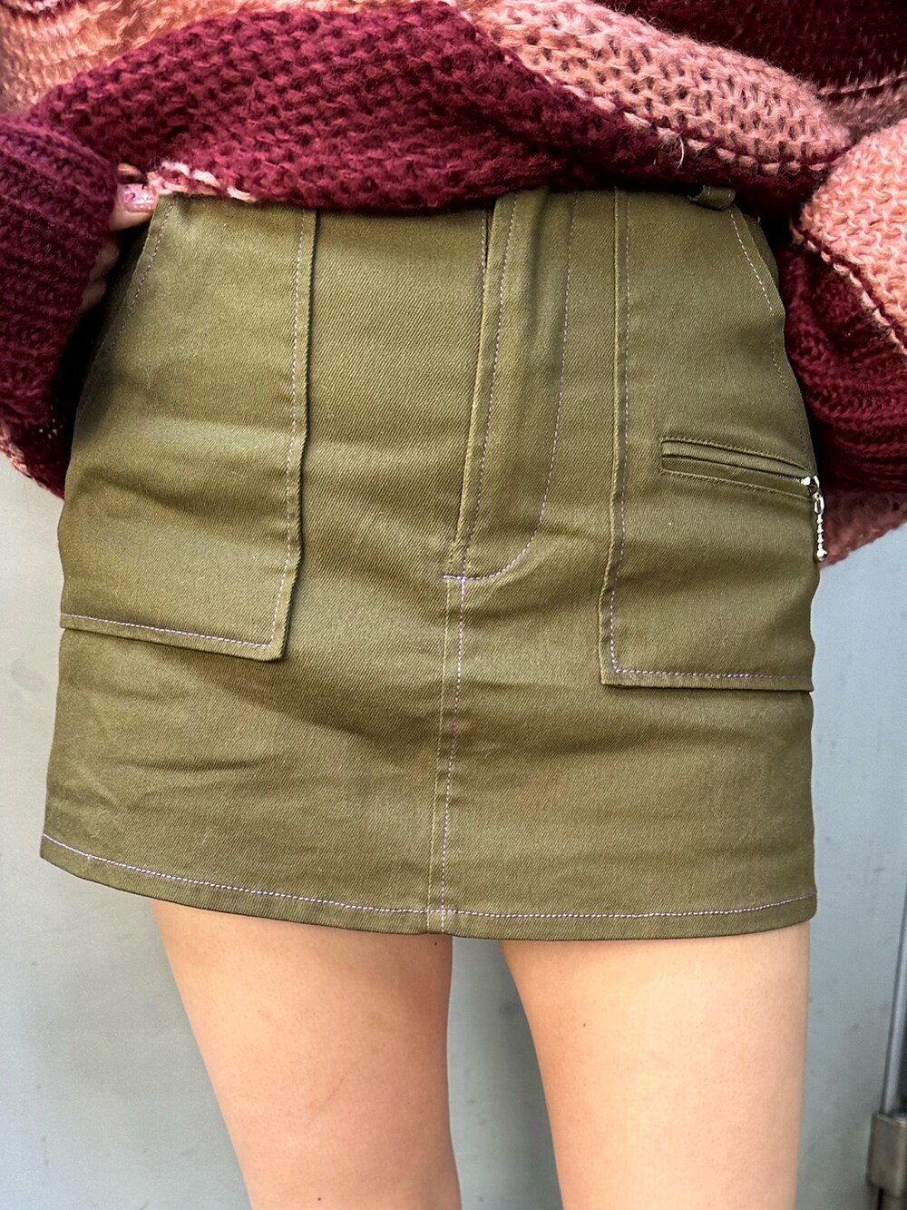 レッド系のニット/セーター、ホワイト系のTシャツ/カットソー、グリーン系のスカートを着用したレディースの秋コーディネートの5枚目の写真