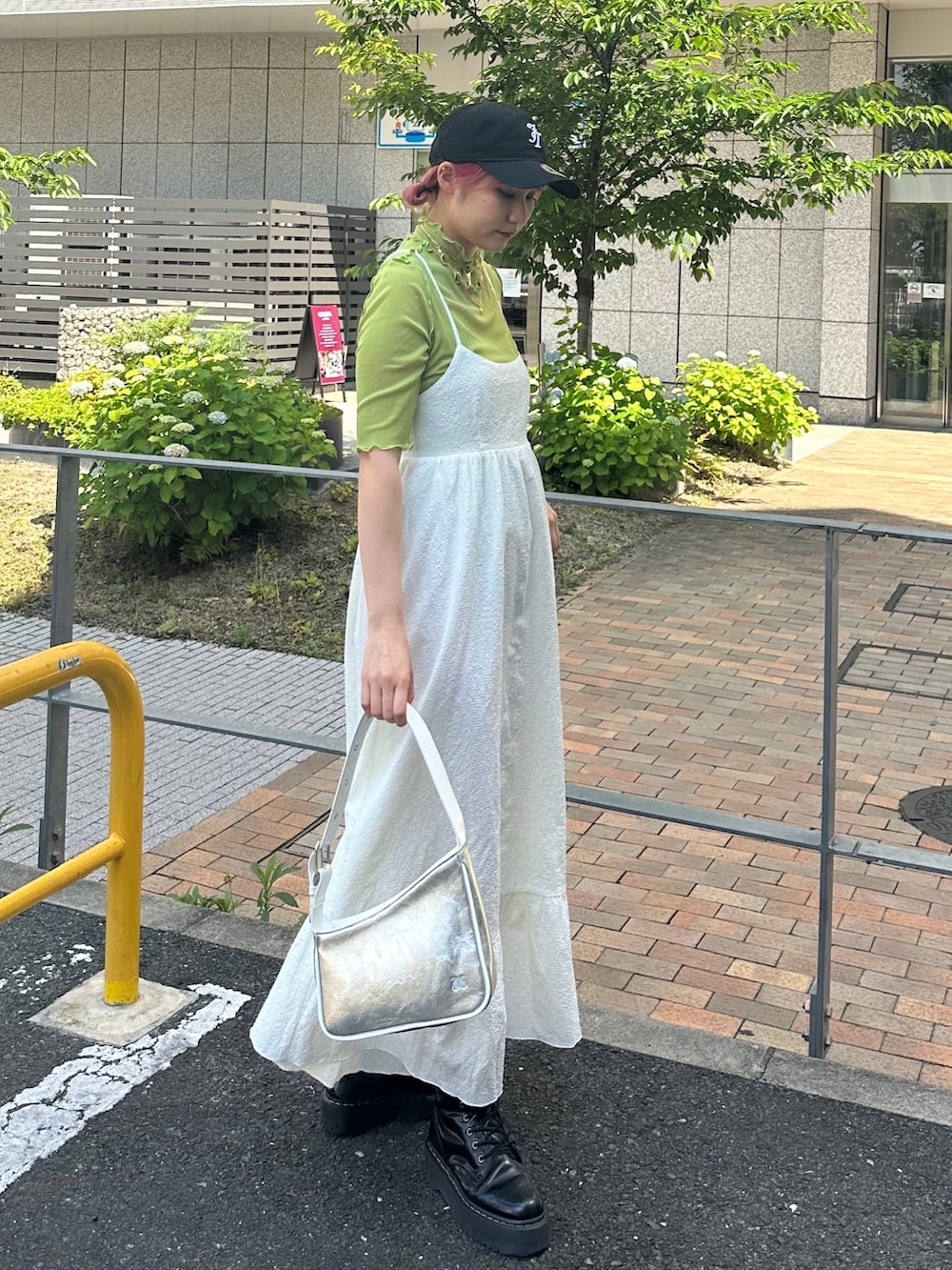 シルバー系のハンドバッグ、ブラック系のブーツ、ホワイト系のワンピースを着用したレディースの春コーディネートの2枚目の写真