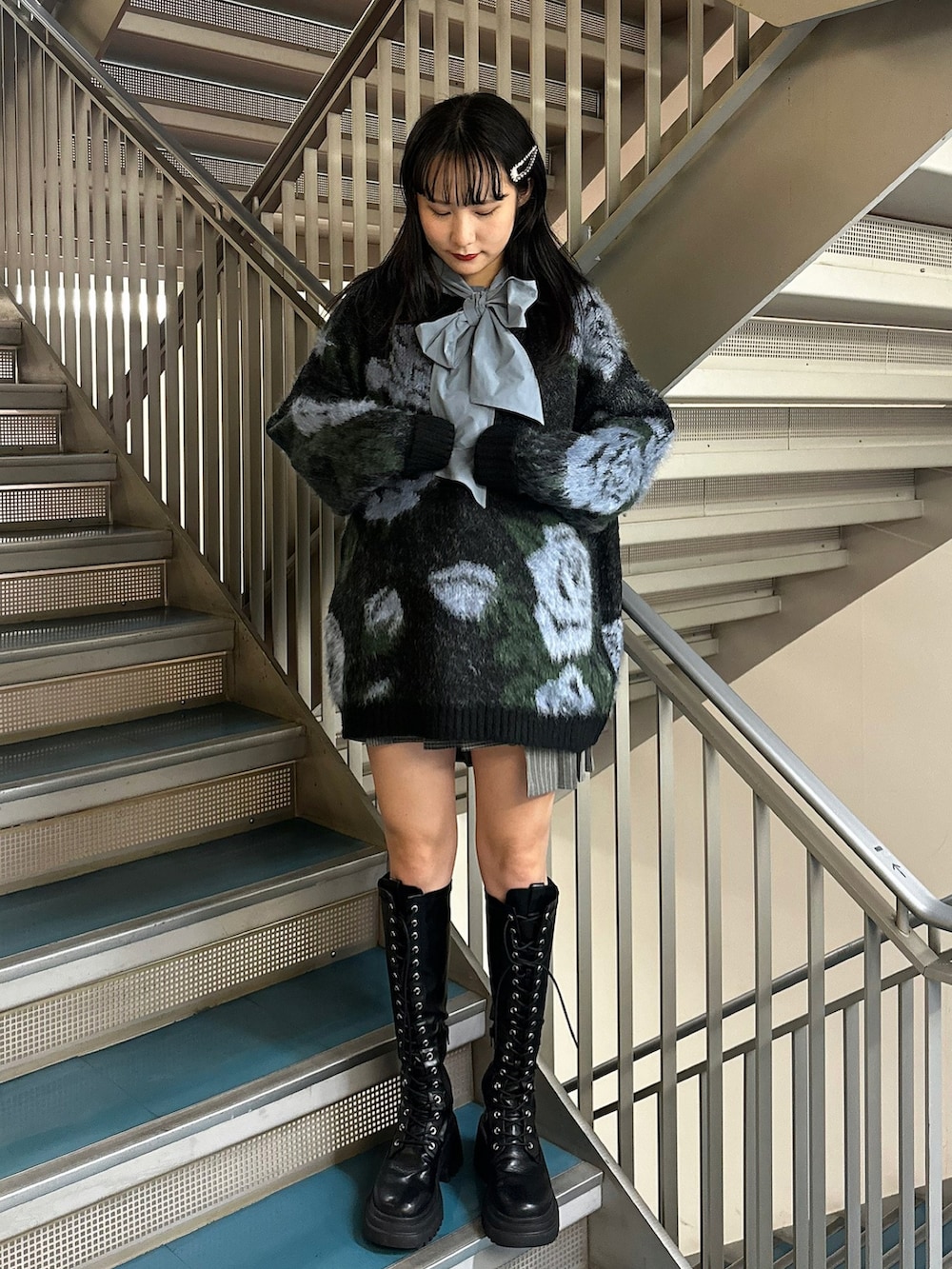 グレー系のスカート、ブラック系のニット/セーター、ブルー系のシャツ/ブラウスを着用したレディースの秋コーディネートの2枚目の写真