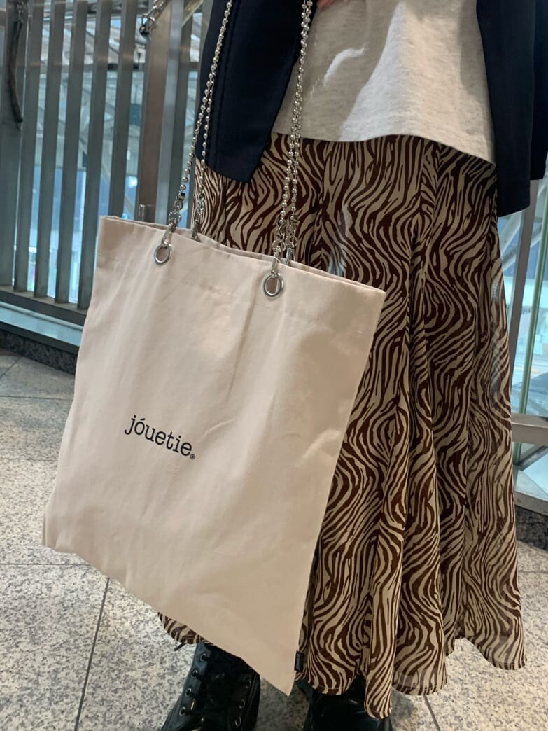 ブラック系のベスト、ホワイト系のトートバッグ、その他のスカートを着用したレディースの春コーディネートの6枚目の写真