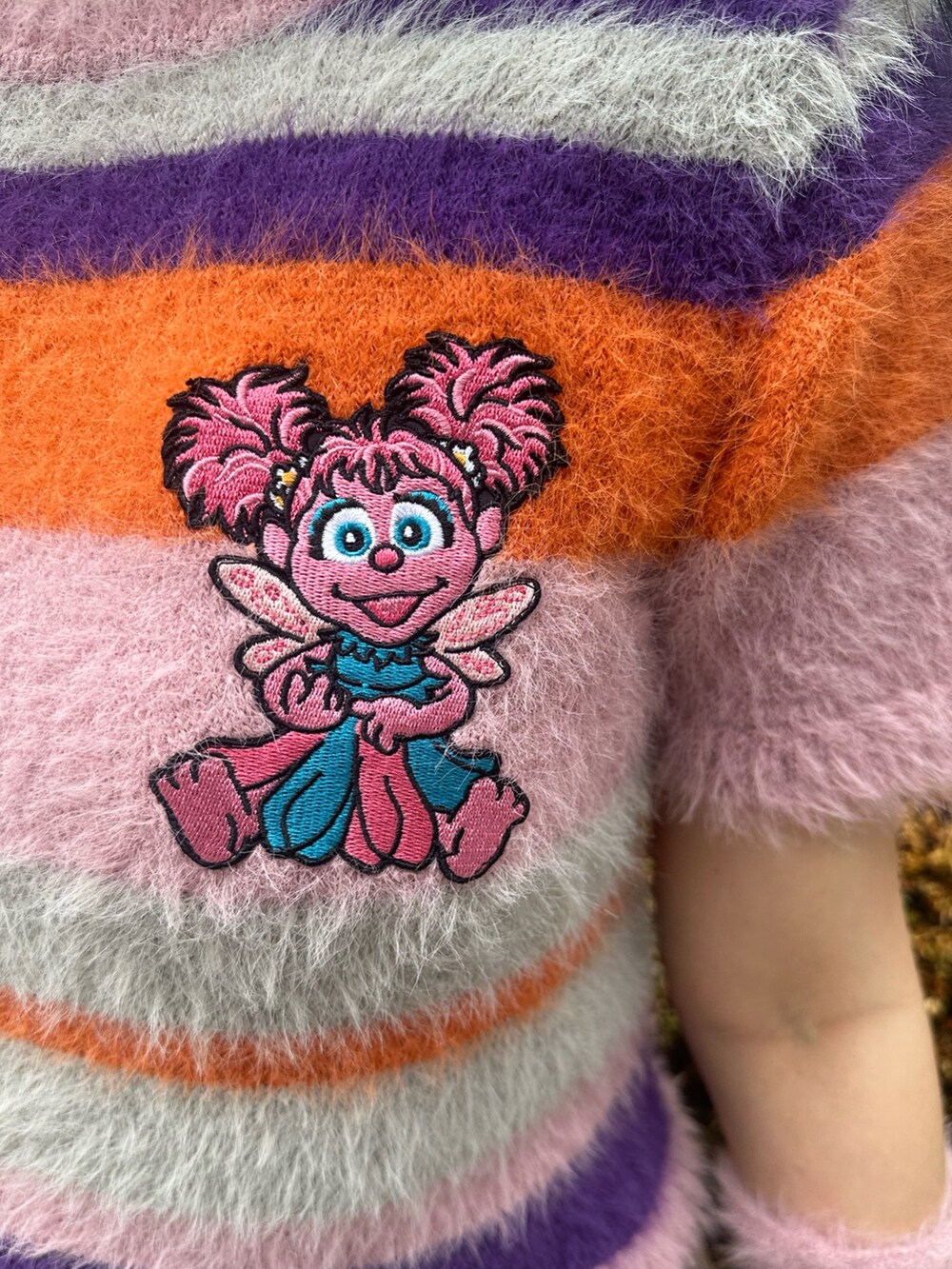 ピンク系のニット/セーター、ベージュ系のスカート、ホワイト系のショルダーバッグを着用したレディースの夏コーディネートの6枚目の写真