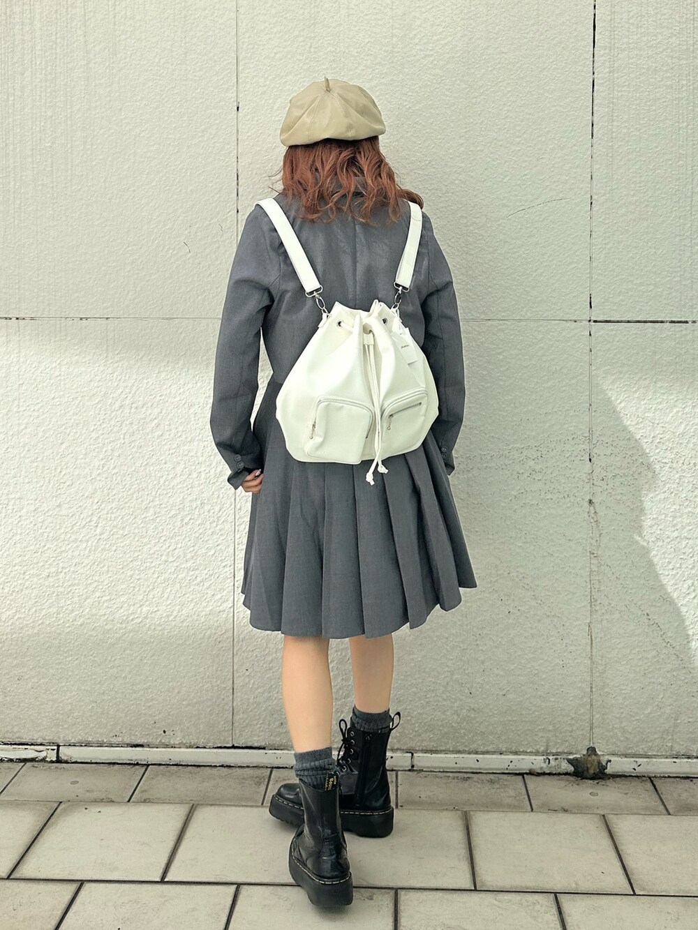 グレー系のスカート、ホワイト系のTシャツ/カットソー、ホワイト系のバックパック/リュックを着用したレディースの冬コーディネートの4枚目の写真