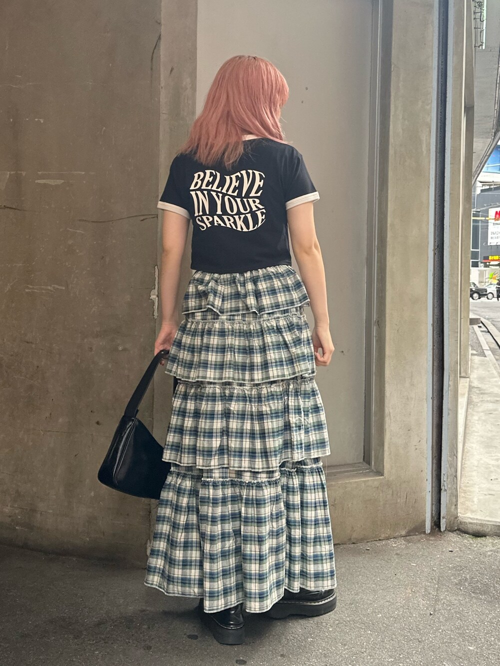 ブラック系のハンドバッグ、ブラック系のTシャツ/カットソー、グリーン系のスカートを着用したレディースの夏コーディネートの2枚目の写真