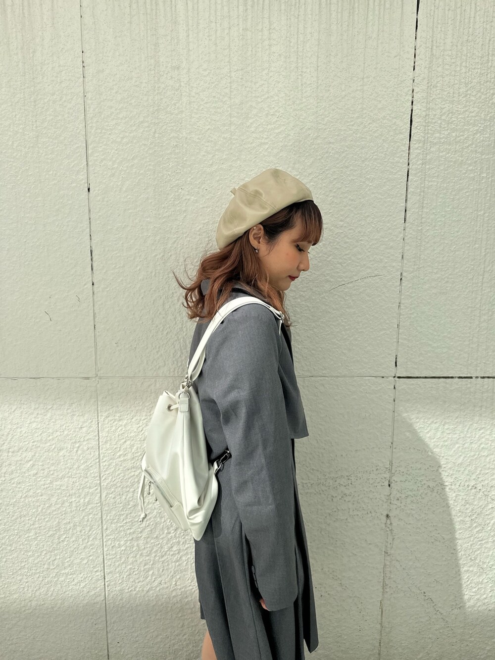 グレー系のスカート、ホワイト系のTシャツ/カットソー、ホワイト系のバックパック/リュックを着用したレディースの冬コーディネートの6枚目の写真