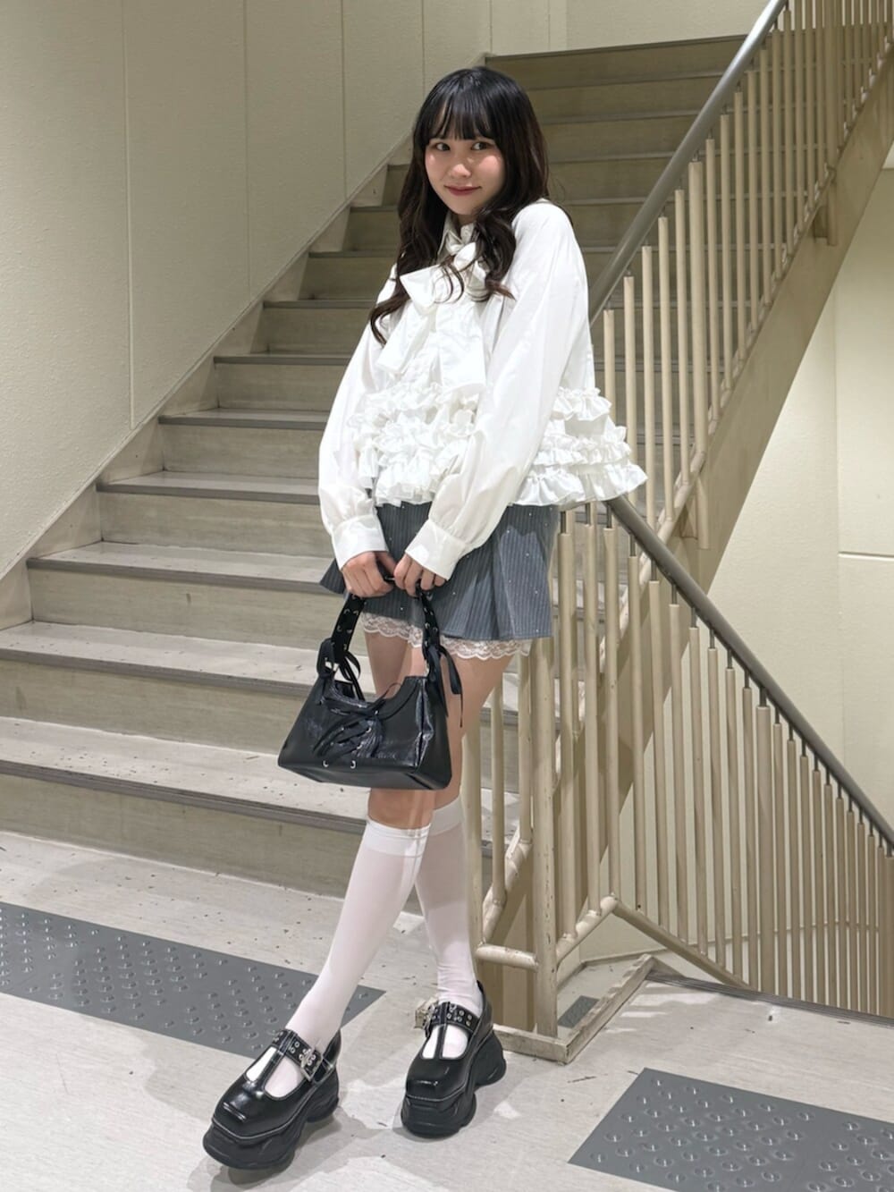 ブラック系のハンドバッグ、ブラック系のローファー、グレー系のスカートを着用したレディースの冬コーディネートの6枚目の写真