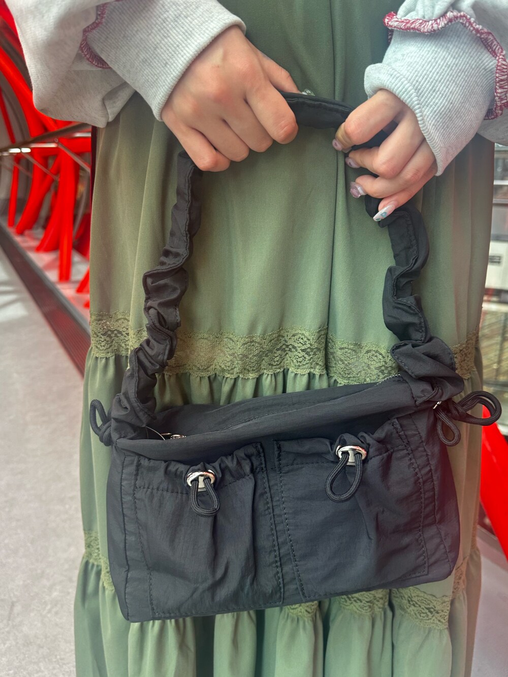 グレー系のスウェット、グリーン系のスカート、ブラック系のショルダーバッグを着用したレディースの夏コーディネートの10枚目の写真