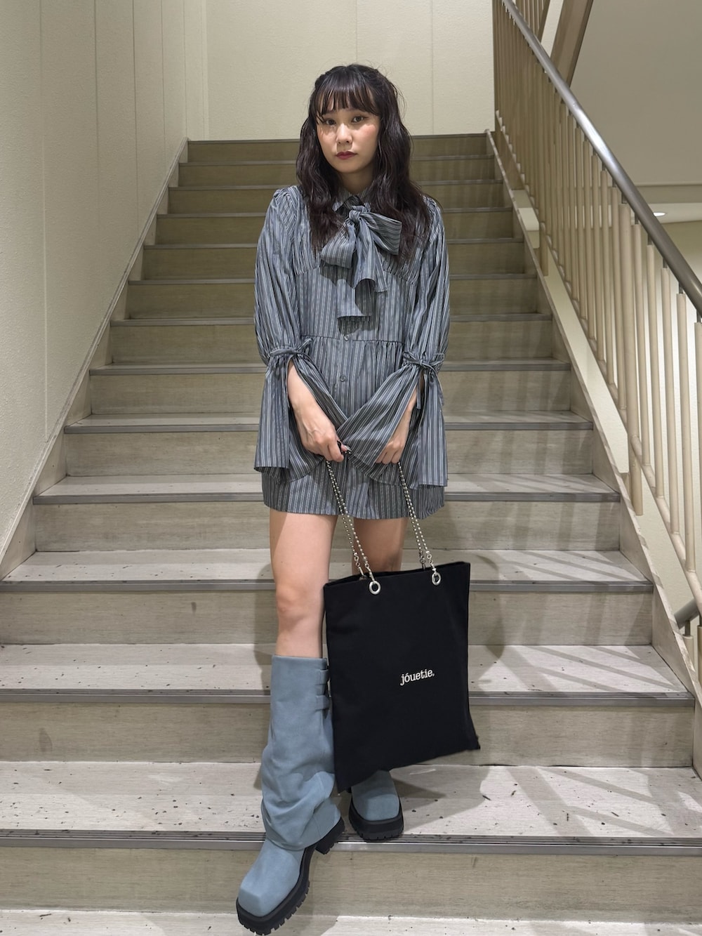 グレー系のシャツ/ブラウス、ブラック系のトートバッグ、ブルー系のブーツを着用したレディースの夏コーディネートの2枚目の写真