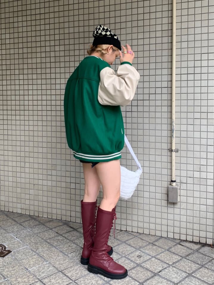 ブラック系のデニムパンツ、ブラック系のデニムパンツ、グリーン系のスタジャンを着用したレディースの秋コーディネートの3枚目の写真