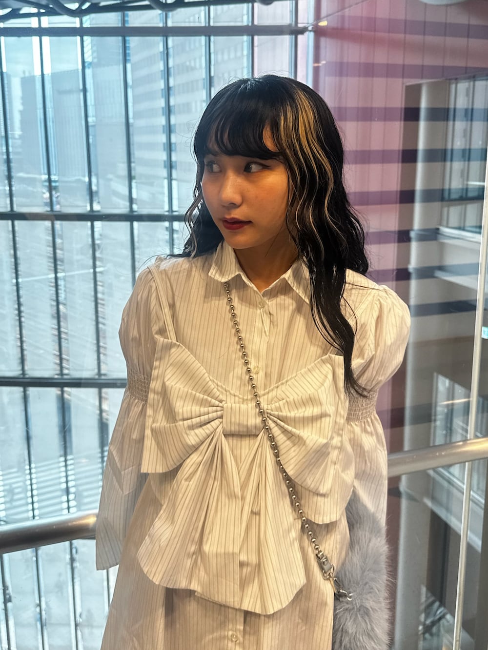 ホワイト系のシャツワンピース、ブルー系のハンドバッグ、ブラック系のブーツを着用したレディースの夏コーディネートの5枚目の写真