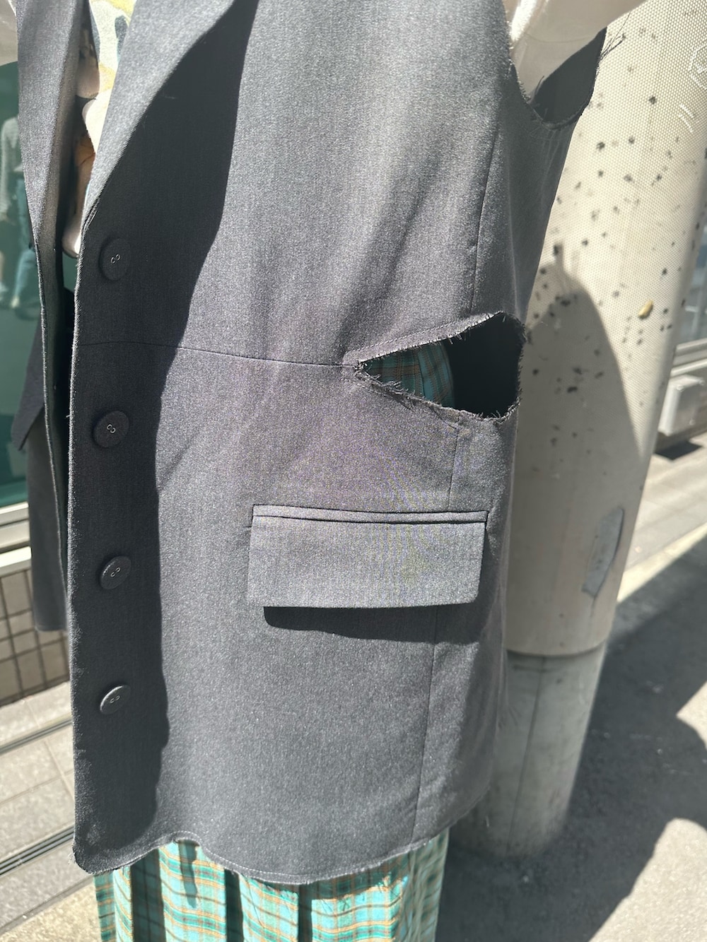 グリーン系のスカート、グレー系のベスト、ホワイト系のTシャツ/カットソーを着用したレディースの春コーディネートの6枚目の写真