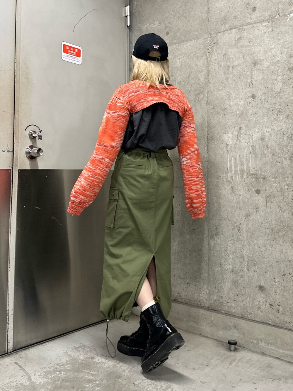 オレンジ系のニット/セーター、ブラック系のTシャツ/カットソー、ベージュ系のスカートを着用したレディースの冬コーディネートの3枚目の写真