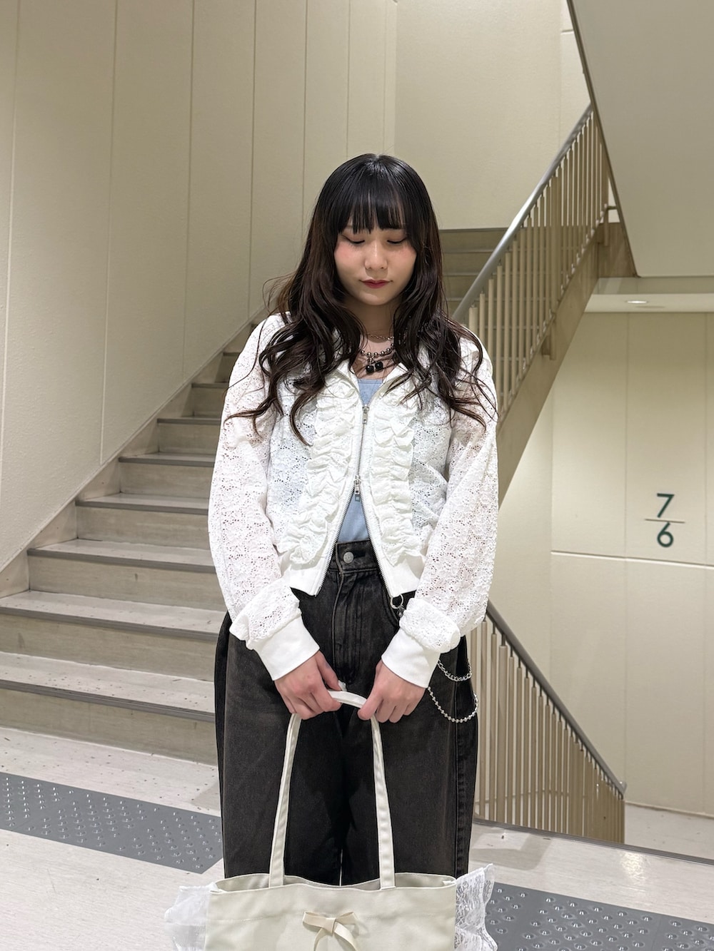 ホワイト系のパーカー、ブラック系のデニムパンツ、ホワイト系のトートバッグを着用したレディースの春コーディネートの7枚目の写真