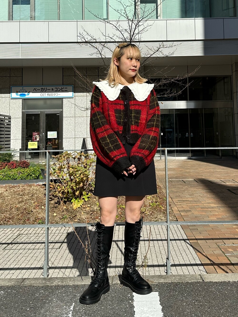 レッド系のカーディガン/ボレロ、ブラック系のワンピース、ブラック系のブーツを着用したレディースの冬コーディネートの2枚目の写真