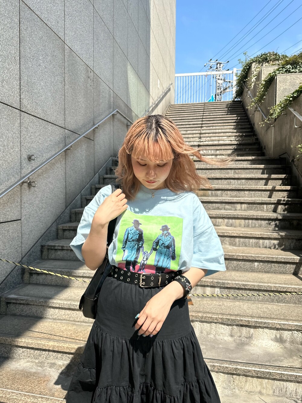 ブルー系のTシャツ/カットソー、ブラック系のショルダーバッグ、ブラック系のスカートを着用したレディースの春コーディネートの3枚目の写真