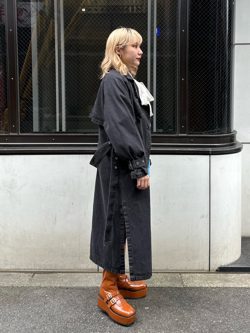 ブラウン系のブーツ、ブラック系のトレンチコート、ブルー系のスウェットを着用したレディースの冬コーディネートの3枚目の写真