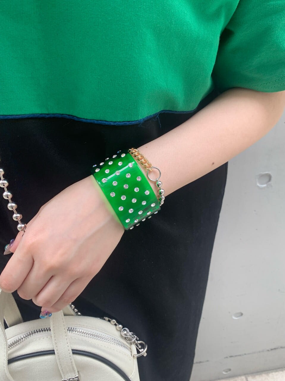 ホワイト系のボストンバッグ、ブラック系のワンピース、グリーン系のバングル/リストバンドを着用したレディースの春コーディネートの7枚目の写真